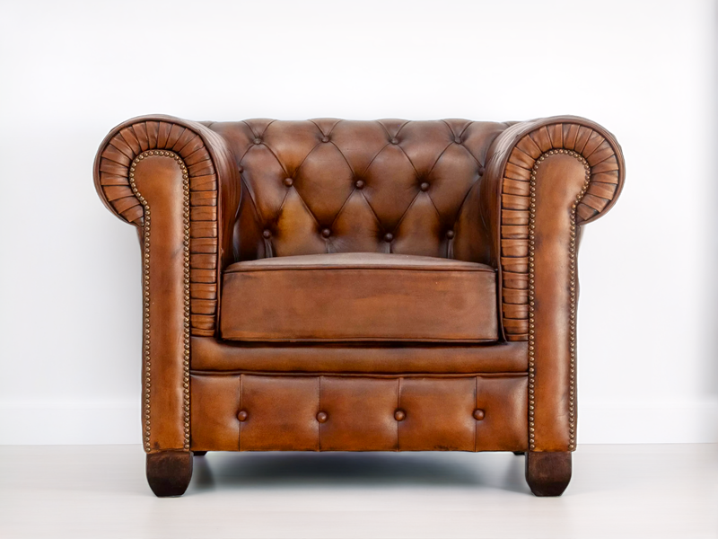 Fauteuil Chesterfield en cuir cognac vu de face, accoudoirs roulés et clous décoratifs
