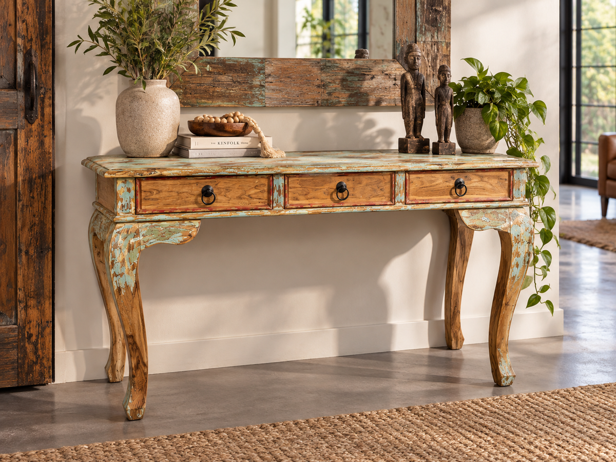 Console en bois patiné à trois tiroirs dans une entrée, sous un miroir en bois