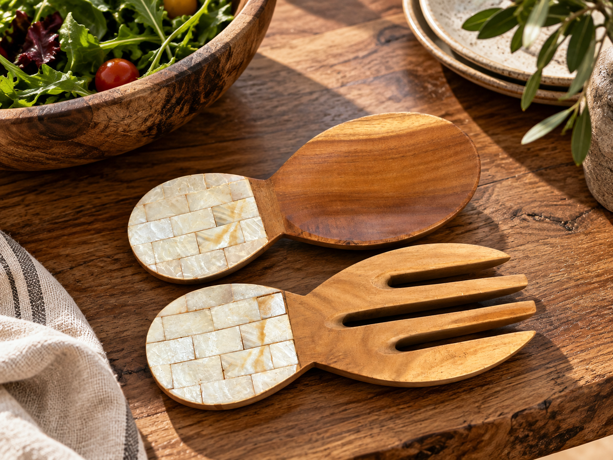 Couverts à salade en bois au manche de nacre, posés sur une table en bois