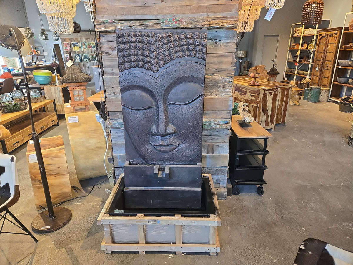 Grande fontaine Bouddha gris foncé au magasin, posée sur sa caisse de transport
