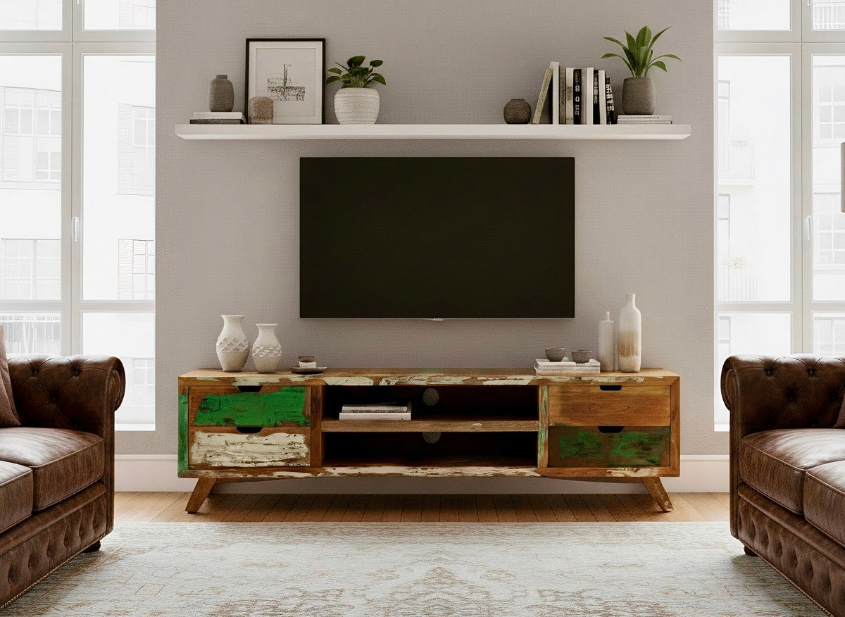 Meuble télé en bois recyclé peint sous un téléviseur, dans un salon aux fauteuils en cuir