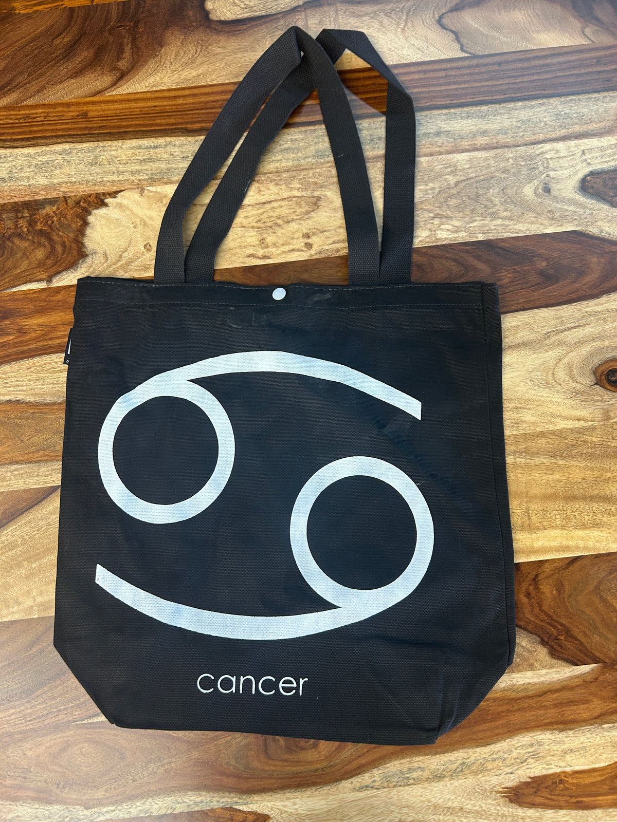 Tote bag noir au symbole du Cancer imprimé en blanc