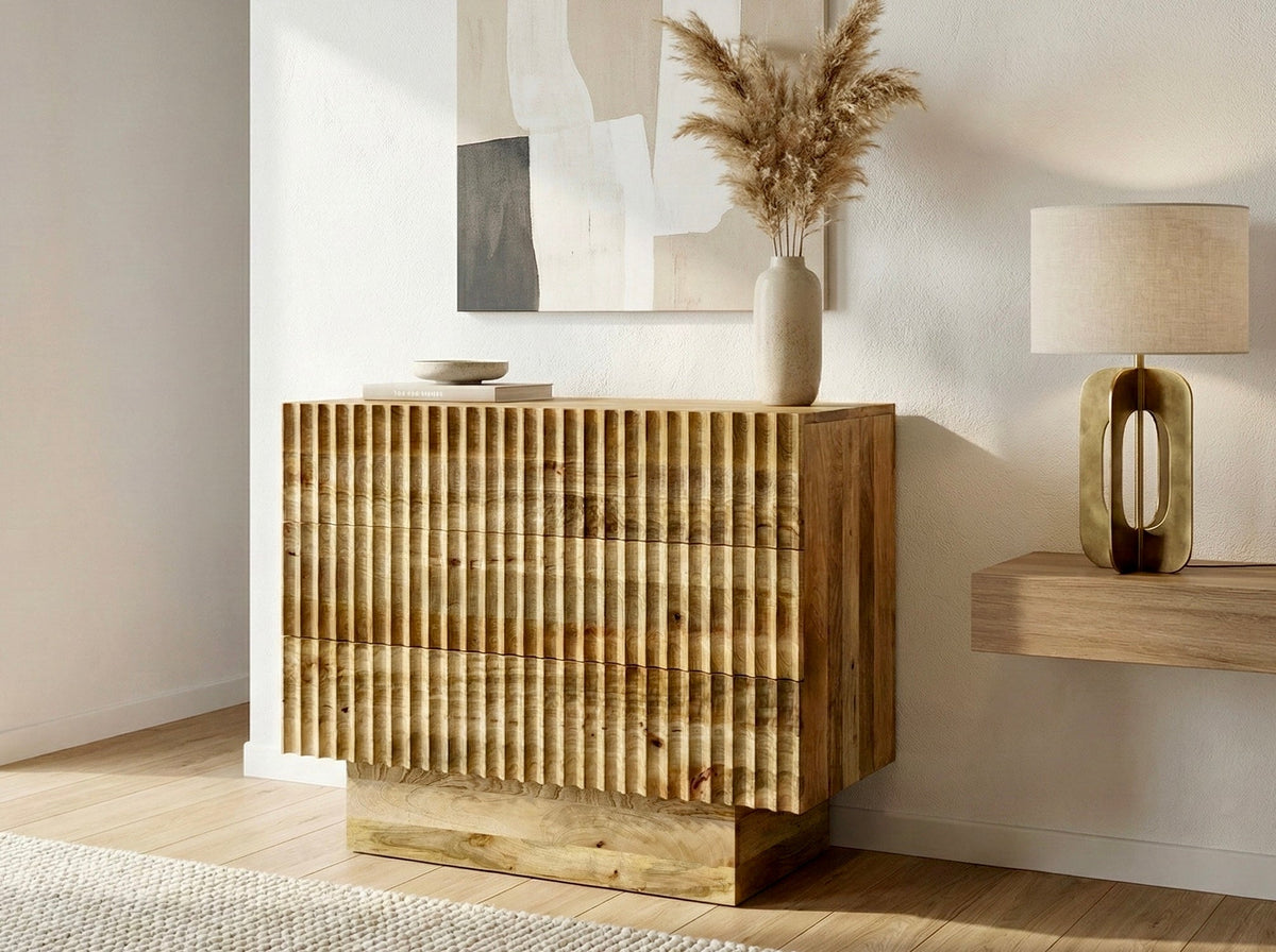 Commode en manguier à façade cannelée, dans un salon clair avec vase de pampas