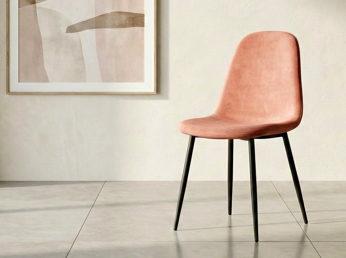 Chaise en velours rose saumon sur pattes en métal noir, devant un mur clair
