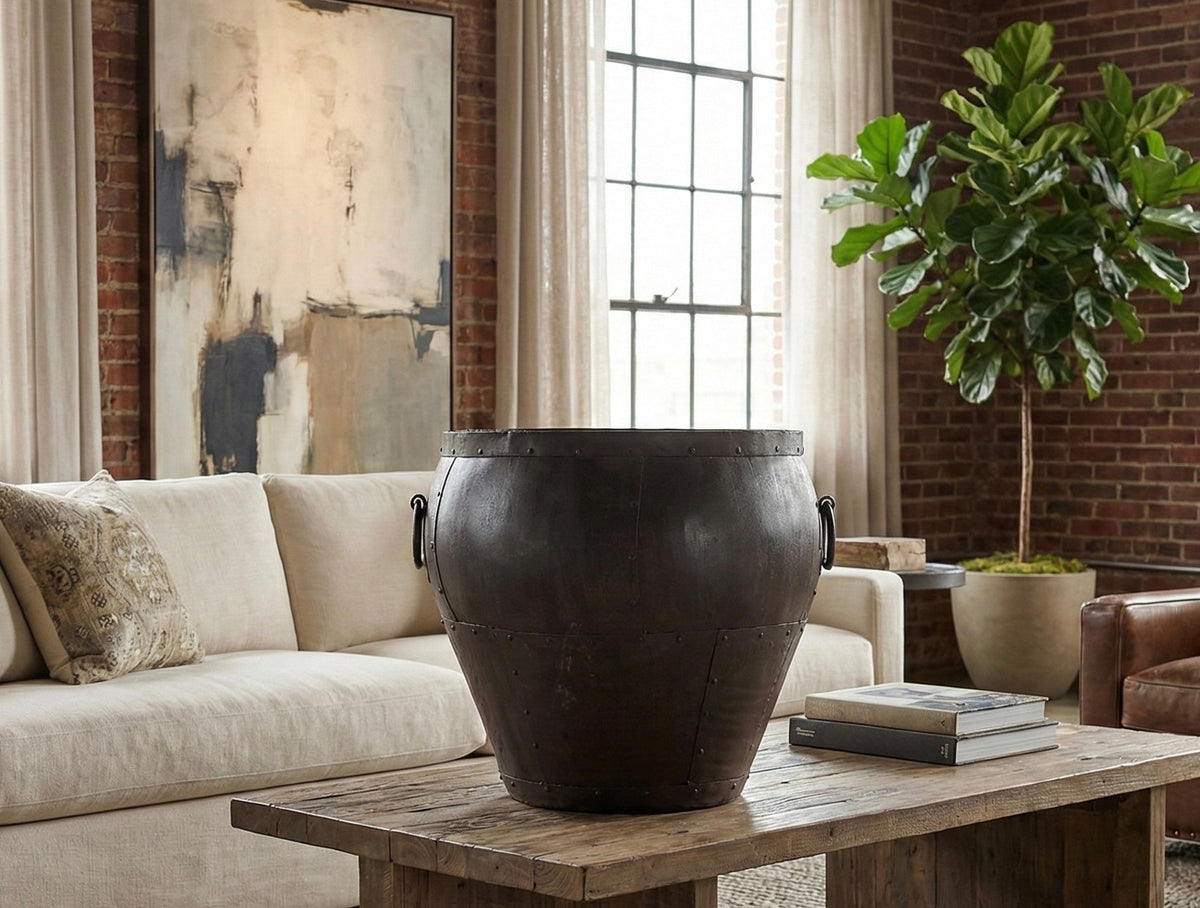 Grand pot en métal foncé posé au sol dans un salon lumineux