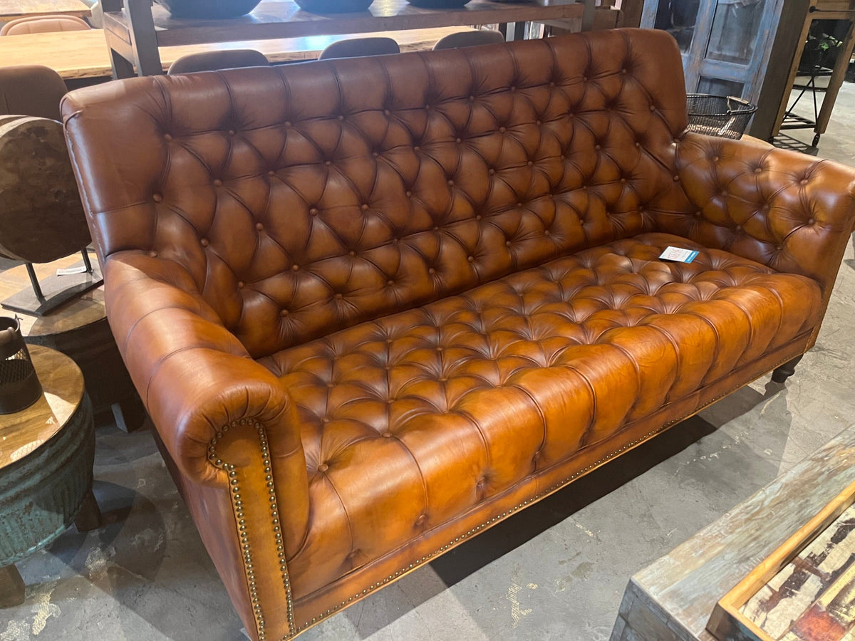 Canapé Chesterfield en cuir cognac capitonné vu de trois quarts