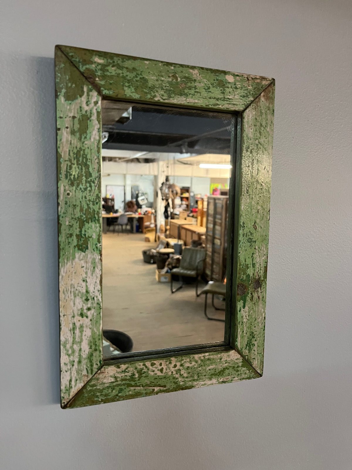 Miroir antique vu de trois quarts, cadre en bois vert écaillé