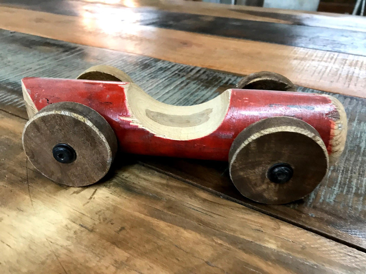 Petite voiture de course en bois peinte en rouge, sur une table