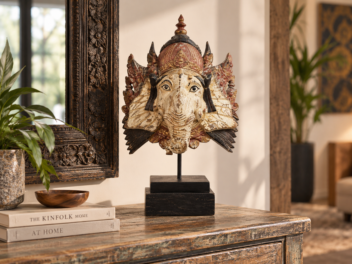 Masque de Ganesh sculpté sur socle noir posé sur une console, près d'un miroir