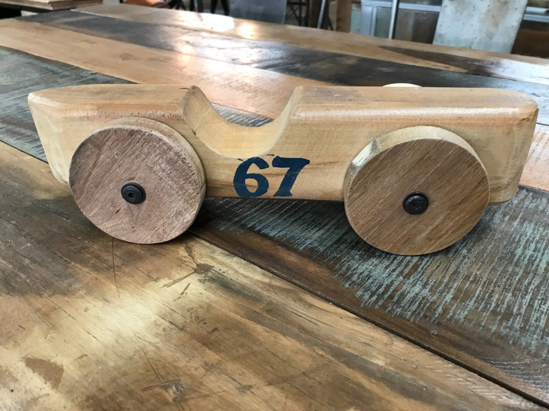 Voiture en bois naturel au numéro 67 peint sur le flanc