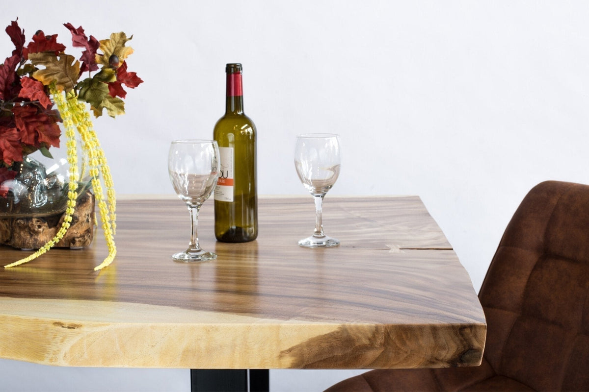 Table à dîner en suar live edge dressée, bouteille et verres posés dessus
